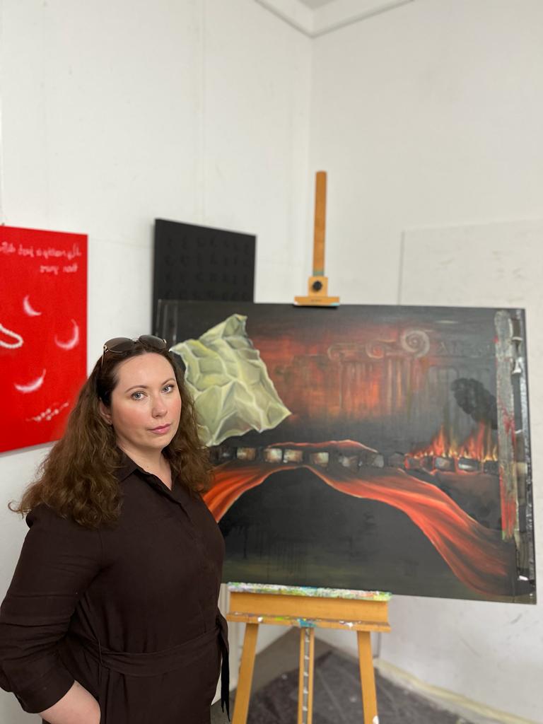 Bild von der Künstlerin Olga Breininger vor einer Staffelei mit einem Ihrer Bilder